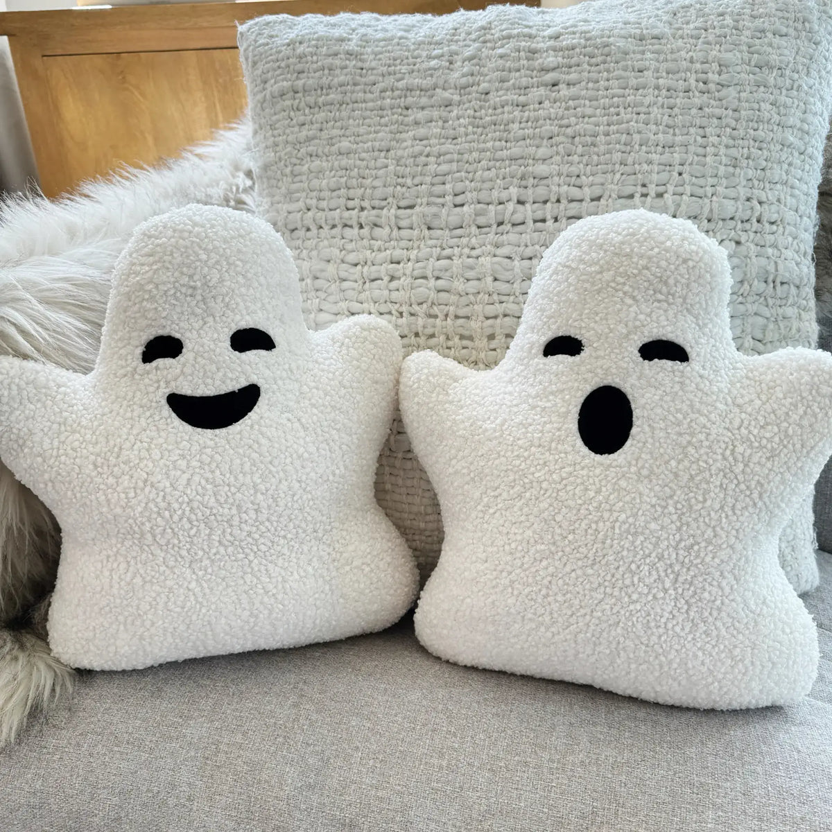 Two holiday sherpa ghost pillows on couch