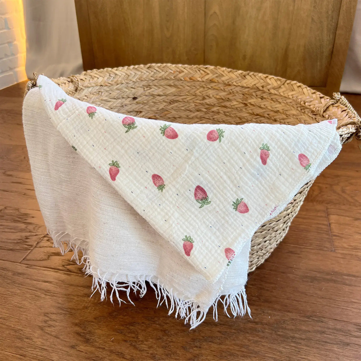 Pink muslin swaddle blanket adorned with sweet strawberries