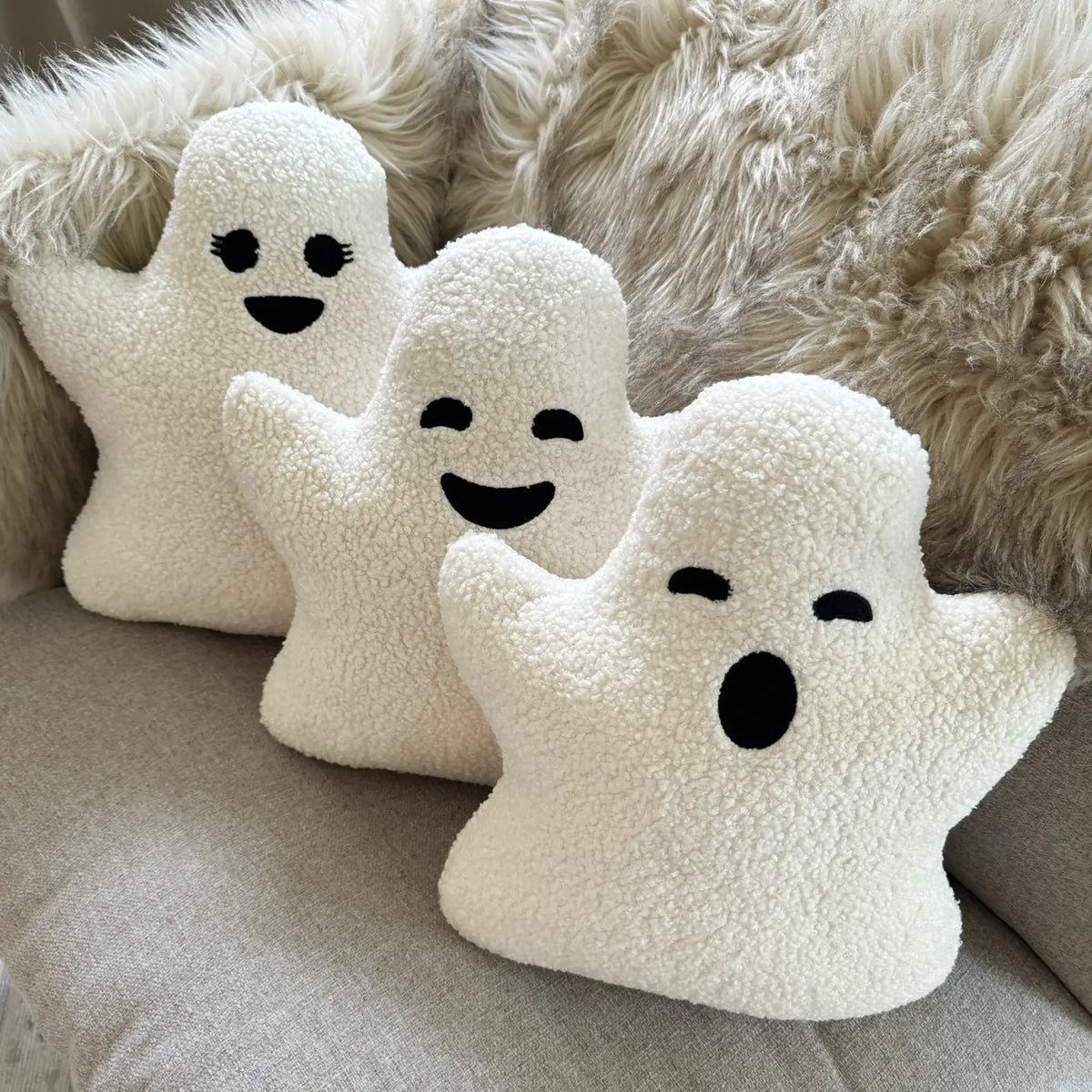 Three ghost pillows on couch with different expressions